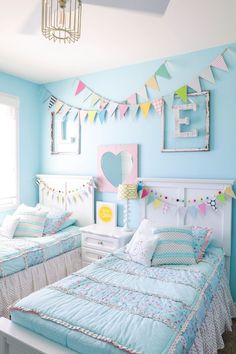 two beds in a room with blue walls and bunting flags hanging from the ceiling