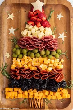 a christmas tree made out of cheese, meats and fruit on a wooden tray