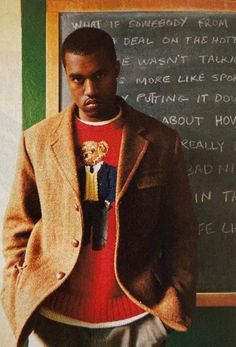 a man standing in front of a chalkboard with writing on it and wearing a jacket