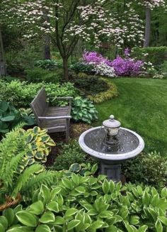 a garden with lots of green plants and flowers in the center, along with two wooden benches