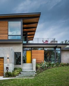 a modern house with wood and glass on the roof, stairs leading up to it