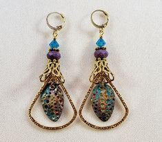 Hand-Painted Earrings. The centerpiece of these earrings are the beautiful hand-painted on copper with resin charms made by Washington State artist Kristi. I accented them with rounded triangle connectors, vintage brass bead caps, purple faceted Czech glass beads and turquoise Swarovski crystal bicone beads. These earrings are 3 inches long including the pure brass round lever back closures. One Of A Kind I can send it gift wrapped (free of charge), if requested. Hand Painted Brass Earrings For Gifts, Hand Painted Brass Earrings As Gift, Hand Painted Metal Dangle Jewelry, Unique Hand Painted Metal Earrings, Bohemian Hand Painted Brass Earrings, Artsy Copper Jewelry With Matching Earrings, Hand Painted Copper Artsy Earrings, Hand Painted Artsy Copper Earrings, Artsy Hand Painted Copper Earrings