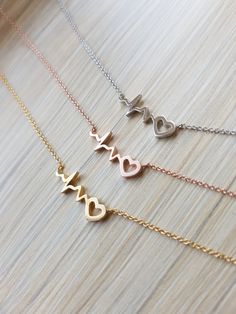 "Simple Dainty Heartbeat Necklace Chain Length: 15\" Chain Extension: Yes Chain Extension Length: 2\" Clasp: Yes Type of Clasp: Lobster Claw Pendant Length: 1/4\" Pendant Width: 3/4\" Chain Width: 1 mm Weight: 2g Metal: Rhodium or gold plated chains, Rhodium plated pendant, Tarnish resistant" Heart-shaped Rose Gold Charm Necklace, Dainty Metal Heart Necklace, Rose Gold Metal Heart Necklace For Mother's Day, Heart-shaped Rose Gold Metal Necklace, Rose Gold Heart-shaped Metal Necklace, Rose Gold Metal Heart Necklace, Hypoallergenic Heart-shaped Metal Necklace, Hypoallergenic Heart Shaped Metal Necklace, Hypoallergenic Adjustable Heart Necklace