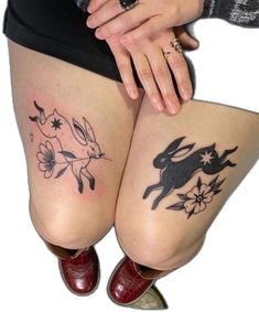 two women with tattoos on their legs, one is holding the other's leg