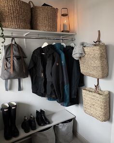 a coat rack with several coats and shoes hanging from it's hooks, next to two wicker baskets