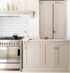 a kitchen with an oven, stove and cupboards in white painted wood paneling