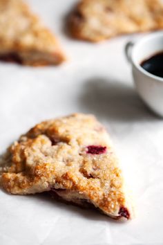 some cookies and a cup of coffee on a white tablecloth next to each other