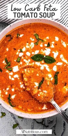 a bowl of tomato soup with spinach and feta cheese on top, next to a spoon