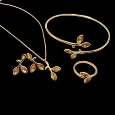 This beautiful collection of nature-inspired jewelry features intricate designs that resemble delicate branches and leaves, with elegant marquise-shaped stones. The collection includes: Gold Plated Set (Yellow Stones): Bracelet: A slender, adjustable bangle with leaf-like yellow marquise stones accenting the branches. The minimalist design gives a chic and timeless appearance. Ring: A matching ring featuring the same leaf motif, with two leaves curving around the finger for a graceful and organic look. Necklace: A fine chain with a pendant shaped like a small branch adorned with two yellow marquise stones. Earrings: Elegant drop earrings that mirror the branch and leaf design, making this set a perfect option for nature lovers seeking a subtle, luxurious touch. Silver Set (Green Stones): B Luxury Intricate Design Bangle Jewelry, Leaf Necklace With Stone, Delicate Gold Leaf-shaped Jewelry, Formal Yellow Gold Leaf Jewelry, Yellow Gold Leaf-shaped Formal Jewelry, Formal Yellow Gold Leaf-shaped Jewelry, Elegant Leaf-shaped Formal Jewelry, Elegant Leaf-shaped Jewelry For Formal Occasions, Adjustable Gold Leaf-shaped Jewelry