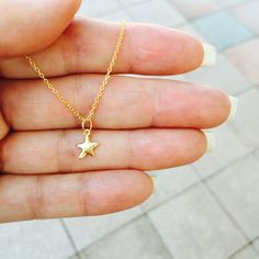 A delicate mini gold star necklace that's perfect for layering. The little star charm is made of 24k gold over sterling silver. This necklace looks great with any outfit whether it be at the office or a night out. Very feminine and dainty. The perfect everyday piece of jewelry for your girlfriend, mom, sister, wife or just something everyday pretty for yourself! This cute star necklace comes packaged in a beautiful gift box ready for gift giving. Each necklace is meticulously hand made in our st Dainty Star-shaped Necklace With Starfish Charm, Dainty Gold Starfish Charm Necklace, Dainty Yellow Gold Star Charm Necklace, Delicate Yellow Gold Charm Necklace With Star Charm, Delicate Yellow Gold Star Charm Necklace, Star-shaped Tiny Necklace For Gift, Tiny Star Necklace For Gift, Cute Gold Jewelry With Star Charm, Gold Star Charm Necklace With Delicate Chain