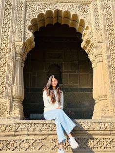 a woman sitting on the ledge of an ornate building