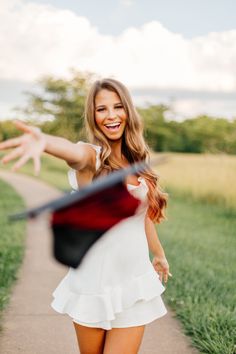 a woman in white dress walking down a path with her arms out to the side