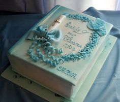 a blue and white wedding cake on top of a sheet covered table with ribbon around the edges