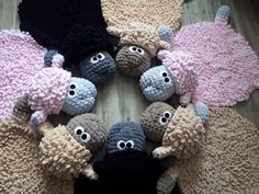 several knitted sheeps are arranged in a circle on the floor with eyes and noses