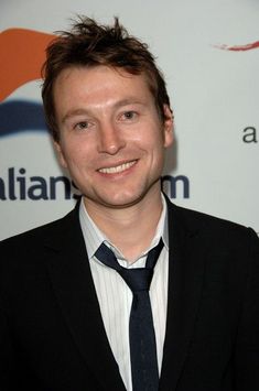 a man in a suit and tie smiling for the camera