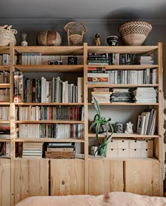 a bookshelf filled with lots of books next to a bed