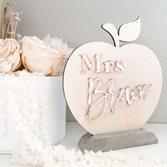 an apple shaped wooden sign with the words mr and mrs brown on it next to flowers