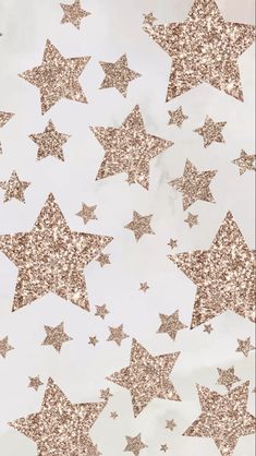 gold glitter stars on white paper with some pink and silver sparkles in the background