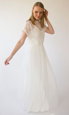 a woman in a white dress is posing for the camera with her hand on her head