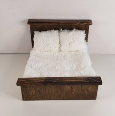 a bed with two pillows on top of it and a wooden frame in the middle