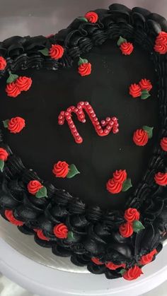 a heart shaped cake decorated with roses and the letter m on it's side