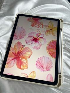 an ipad with flowers on it sitting on a bed