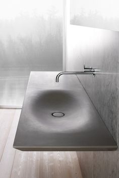 a bathroom sink sitting on top of a wooden floor next to a wall mounted faucet