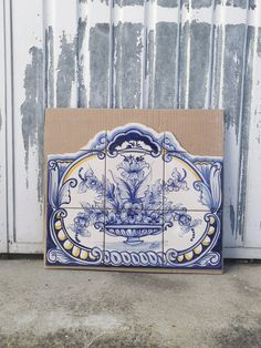 a blue and white tile box sitting in front of a wall with peeling paint on it