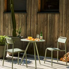 two chairs and a table on a wooden deck near a potted cacti