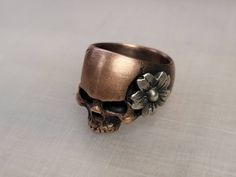 shibuichi (10% silver, 90% copper) with a sterling silver cherry blossom  Size 7.75 18mm tall, 15mm wide across the face 8mm wide band Japanese Skull, Surf Jewelry, Skull Flower, Skull Rings, Silver Skull Ring, Flower Birthday, Red Skull, Flower Skull, Skull Ring