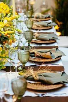 a long table set with place settings and yellow flowers in vases on each side