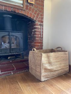 a basket sitting on the floor next to a fire place in a room with a brick fireplace