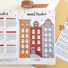 an open planner with buildings on it next to a roll of washi tape and a marker