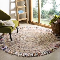 a living room with a green chair and a round rug on the floor in front of a window