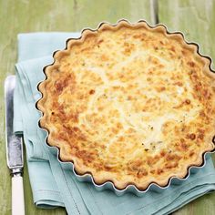 a pie sitting on top of a wooden table next to a knife and fork,