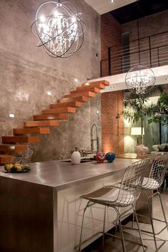 a modern kitchen with stainless steel counter tops and bar stools next to the stairs