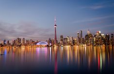 the city skyline is reflected in the water at night, as seen from across the lake