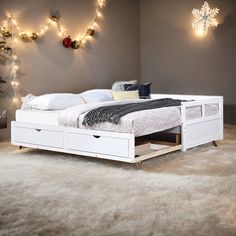 a white bed sitting on top of a carpeted floor next to a christmas tree