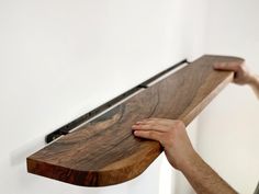 a man is holding the edge of a wooden shelf