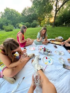 four women sitting at a picnic table eating and drinking