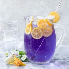 a pitcher filled with purple liquid and lemon slices