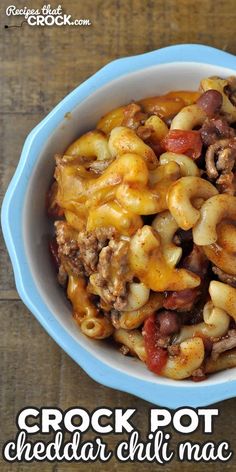 a blue bowl filled with cheese and chili macaroni casserole on top of a wooden table