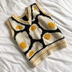 a knitted sweater with an egg pattern on the front and back, sitting on a bed