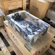 a marble sink sitting on top of wooden pallets in a room filled with boxes