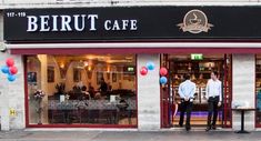 two men are standing in front of a restaurant