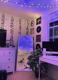 the room is decorated with string lights and pictures on the wall above the computer desk