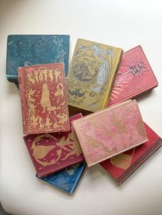 five different colored books sitting next to each other on top of a white countertop