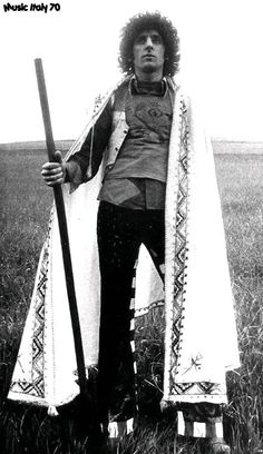 an old photo of a man in costume holding a staff and standing in a field