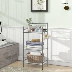 a bathroom with white walls and wood flooring, including a metal shelf filled with towels