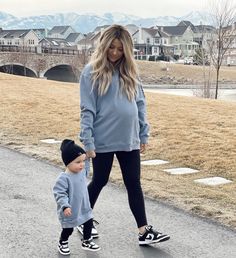 a woman and child are walking down the street with their hands in each other's pockets